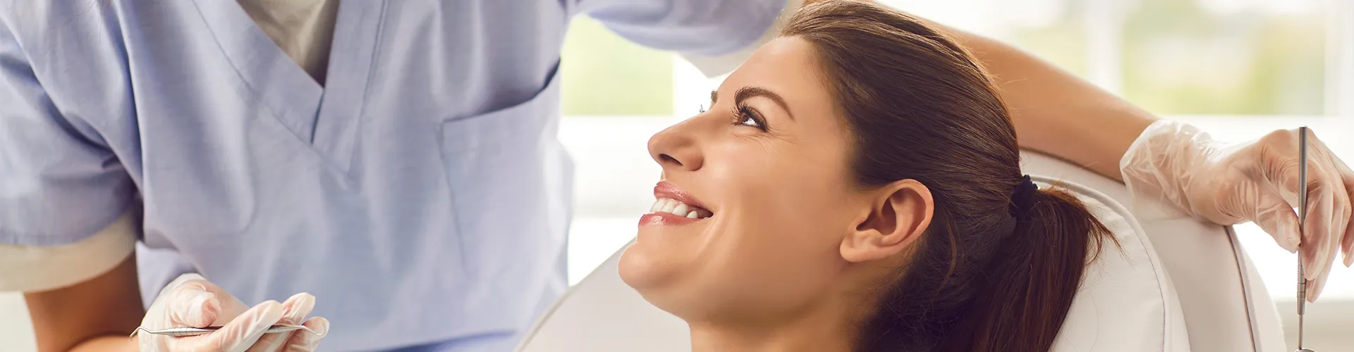 dentist wearing mask talking to smiling woman in dental chair